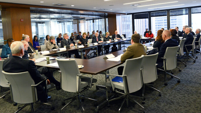 Representatives of 20 colleges meet around a table
