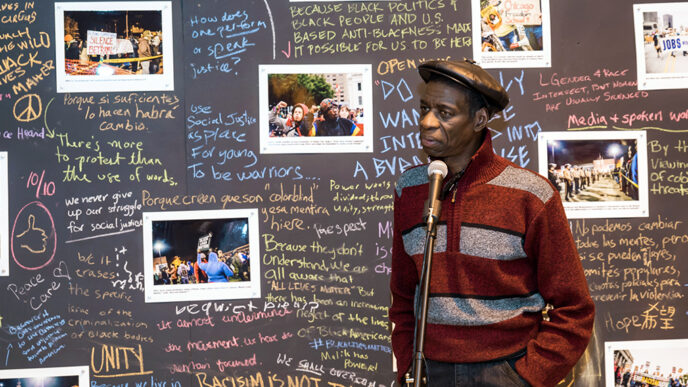 Darrell Cannon in front of photos and handwritten statements about police brutality