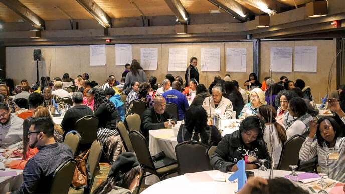 A room full of parents during a family engagement workshop at Youth Guidance|A parenting skills teacher talks to group of adults in a classroom at Chicago Youth Centers|