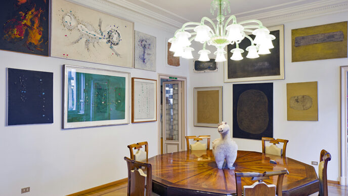 A dining room with an ornate wooden table and several paintings on the walls
