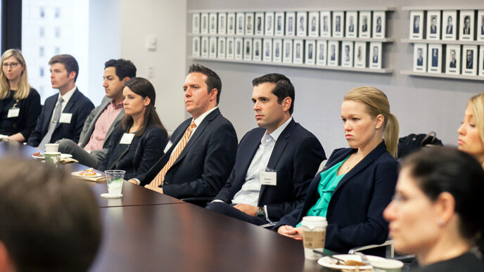 A row of people seated at a ing boardroom table listening intently|James Vender|Pam Berkowitz