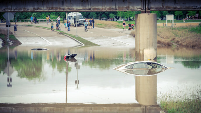 A flooded highway where two cars are partially submerged