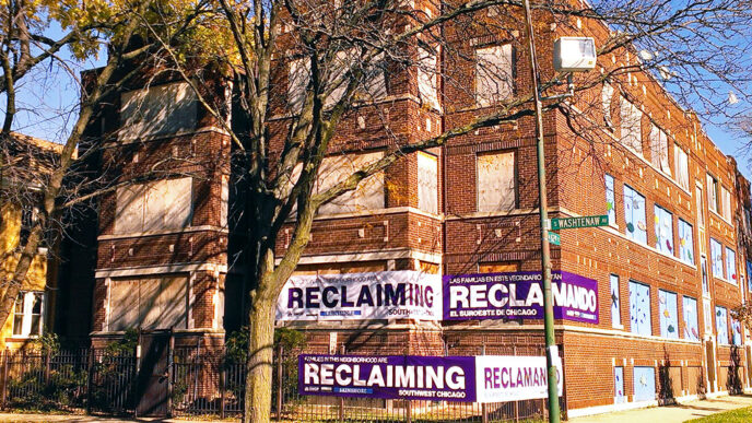 A multi-unit brick building with boarded windows