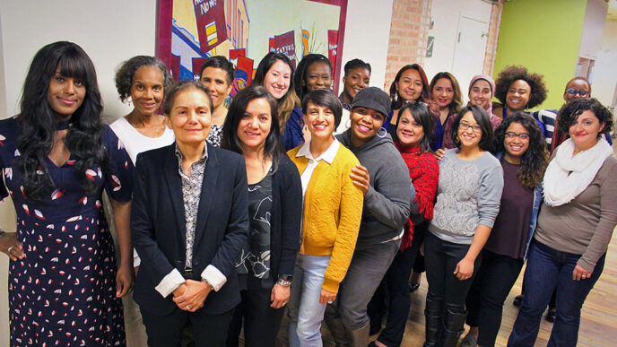 Nineteen women standing in a group indoors