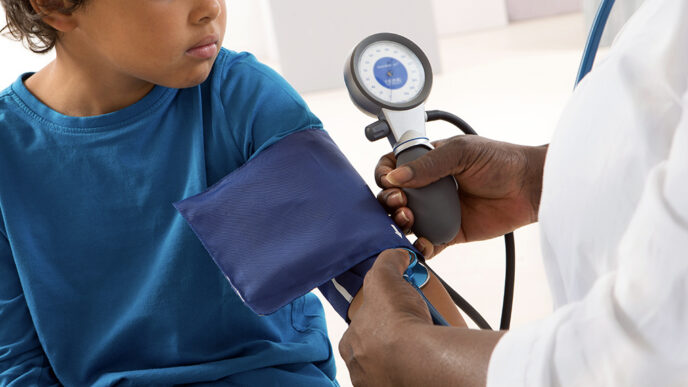 Close-up view of a young child’s arm wrapped in a blood pressure cuff