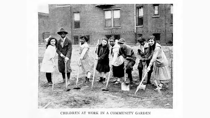 Old black-and-white photo of a town of children holding garden tools