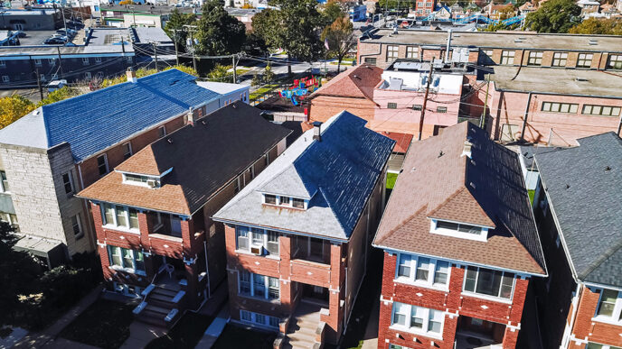 Aerial view of a residential neighborhood with multi-family brick buildings in the foreground and a school with playground behind