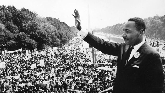 Rev. Dr. Martin Luther King Jr. stands on a podium overlooking the crowd at the 1963 March on Washington|Four men