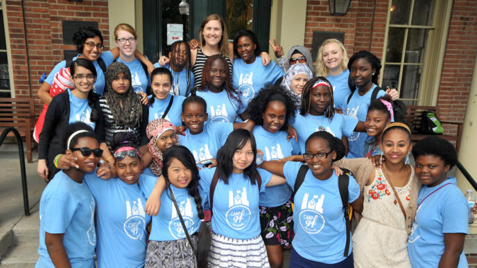 Blair Brettschneider stands on a staircase with a group of students from GirlForward