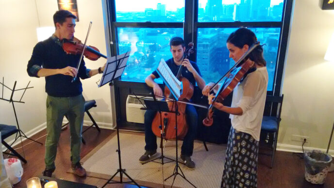 Three string musicians from GroupMuse tune up in a Chicago apartment