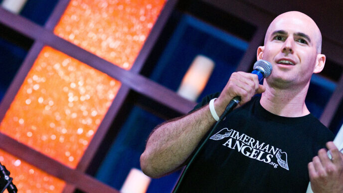 Jonny Imerman speaking on stage|Jonny Imerman addresses an audience from the stage