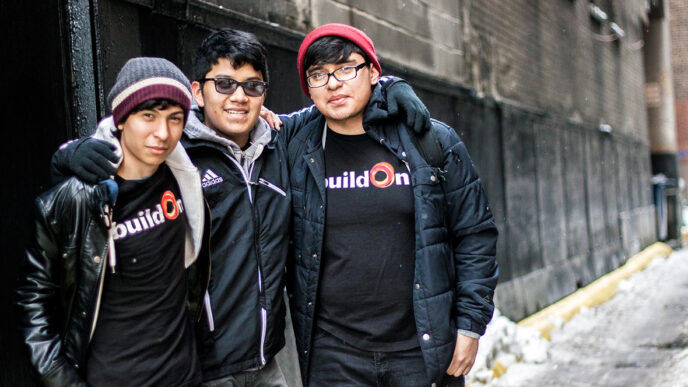 Carlos Leon with two fellow students from the BuildOn program|Lunch bags and handmade greeting cards prepared by students|Three students hand-stitch fleece fabric into warm winter hats