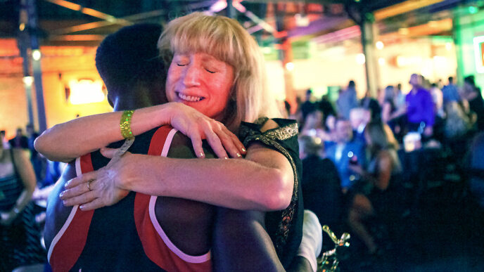 Sally Hazelgrove hugs a young boxer holding a gold trophy|||||||