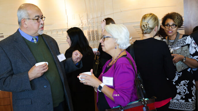 Guests in conversation at the Nuestro Futuro reception|Guests listening and smiling|Panelists seated on the stage|