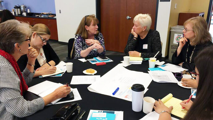 A small group in conversation during an information session hosted by The Lake County Community Foundation|Bar chart contrasting the age distribution of Lake County's population in 1990 and 2025. Young and middle-aged adult populations are declining