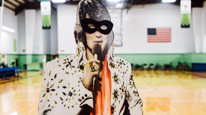 A cardboard cut-out of Elvis Presley in the Lambs Farm gymnasium|A portrait of the Lambs Farm Elvis Club members|Jeanne Curtin shares Halloween stickers with an Elvis Club member|
