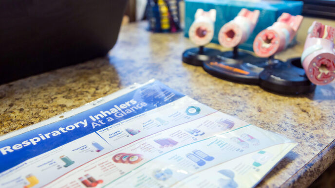Models of bronchial tubes and fact sheets about inhalers inside a mobile asthma screening clinic|Helen Redding stands in front of the mobile clinic talking to a group of young people|A young boy waits inside the mobile asthma screening van