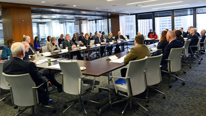 Representatives of 20 colleges meet around a table