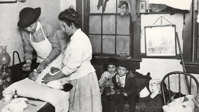 Archival photo of a visiting nurse from Hull House administering eye drops to a baby while its mother and two siblings look on