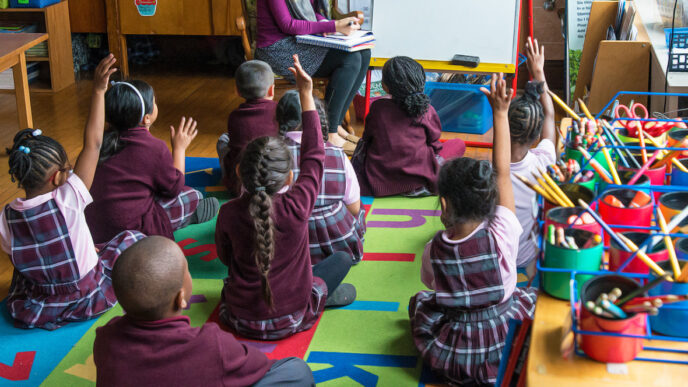 Children sitting on the floor in a first-grade classroom raise their hands|Jenny Fortner and companions at a gala supporting Special Olympics Illinois