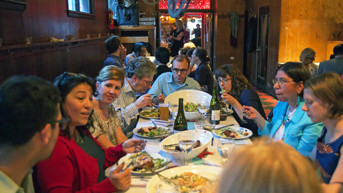 Guests enjoying dinner and talking at an On the Table event at the Hideout