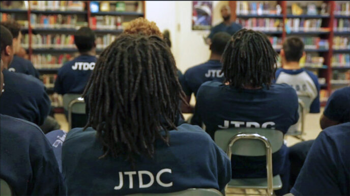 Students in the Cook County Juvenile Temporary Detention Center library|Three young residents in the Juvenile Temporary Detention Center wearing JTDC t-shirts|