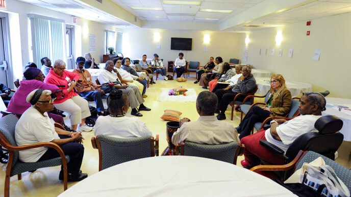 A group gathered in discussion at the Kingston Place senior residence|Laura Morgan addresses the group at her On the Table lunch