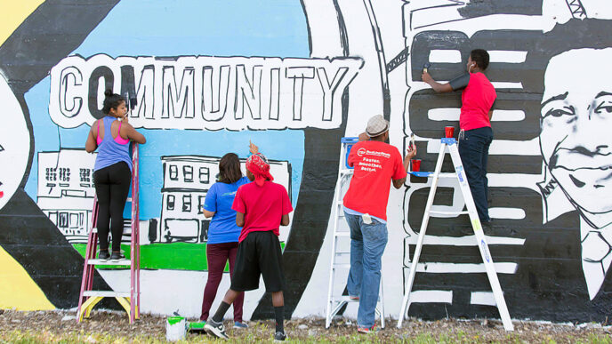 Volunteers create a mural illustrating local history in the Greater Grand Crossing neighborhood