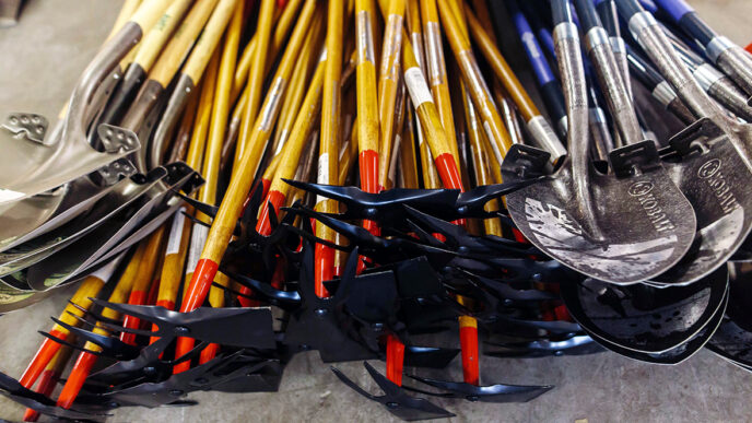 A collection of garden tools|Organizing a collection of garden hoes at the Chicago ToolBank|A volunteer holding a paintbrush|Susan McDonald at the ToolBank warehouse|Two children painting wooden handles for shovels