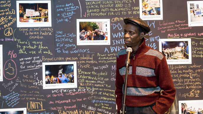 Darrell Cannon in front of photos and handwritten statements about police brutality