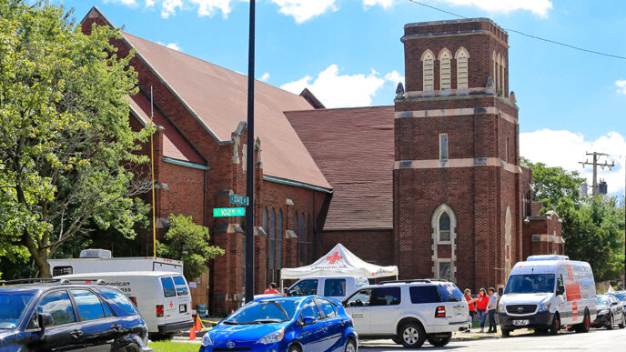 A church in Chicago's Roseland neighborhood|A man on a ladder installs a smoke alarm on a wall|A volunteer with a clipboard reviews a fire safety checklist|Two volunteers on a doorstep talking with a home owner