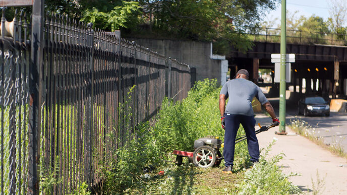 A man mows the grass in a public space in Grand Crossing