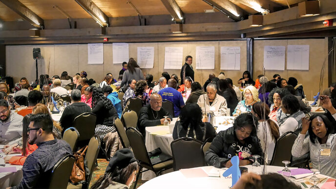 A room full of parents during a family engagement workshop at Youth Guidance|A parenting skills teacher talks to group of adults in a classroom at Chicago Youth Centers|