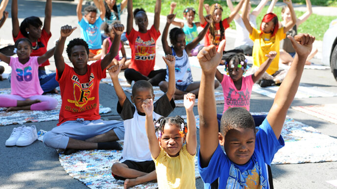 A group of kids sitting cross-legged and stretching