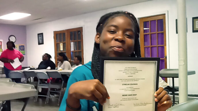 Gymelah Coleman holds a certificate and smiles|||Twenty children smile and pose with their graduation certificates