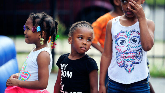 Three girls standing and waiting for their turn to perform|A crowd gathered in a parking lot