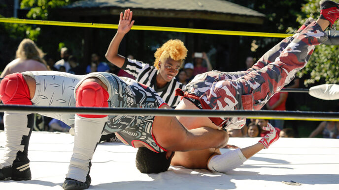 A wrestler attempts to pin an opponent while a referee watches|A wrestler makes an entrance toward the ring