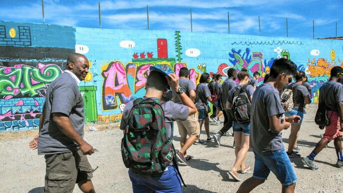 A group of students walking past a brightly colored mural|Chicago Park District Commissioner Jesse Ruiz shakes hands with a young man in the Trust's office boardroom|A group of students on a lawn at the University of Chicago|Matthew Brewer