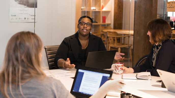 Brandies Meva'a and colleagues meeting in a conference room|Sandee Kastrul