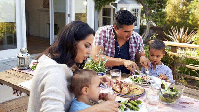 A mother and father sit at an outdoor dining table