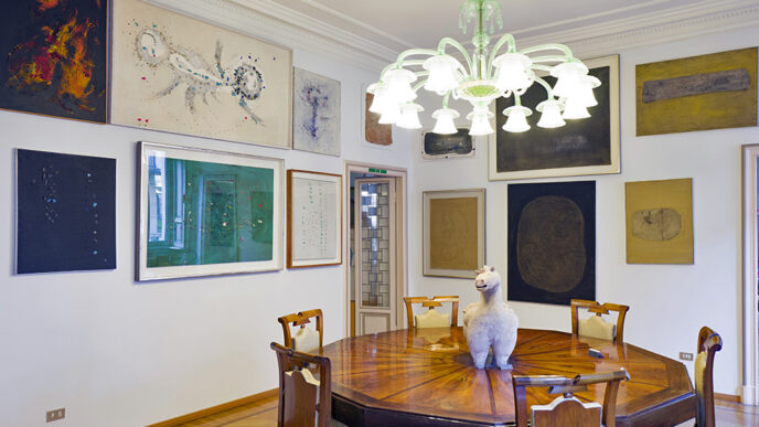 A dining room with an ornate wooden table and several paintings on the walls