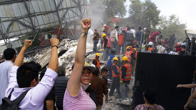 Rescue workers in safety vests and hard hats climb through the rubble of buildings