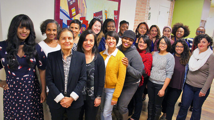 Nineteen women standing in a group indoors