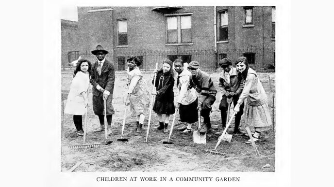 Old black-and-white photo of a town of children holding garden tools