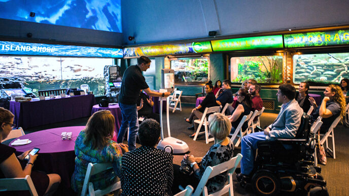 A man demonstrates an electronic device in the center of an aquarium display hall
