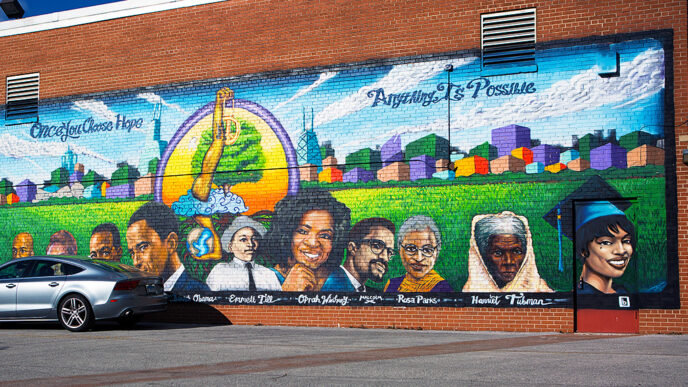A mural on a brick wall shows historic figures in front of Chicago's skyline with the words Once You CHoose Hope Anything Is Possible