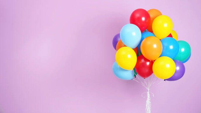 A bunch of colorful balloons against a purple background