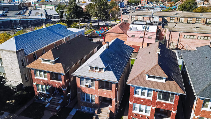 Aerial view of a residential neighborhood with multi-family brick buildings in the foreground and a school with playground behind