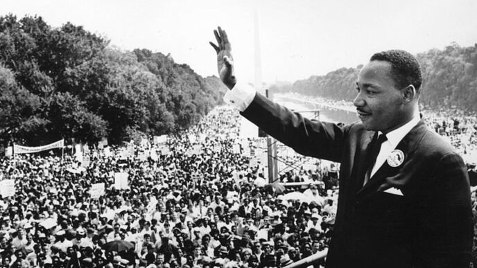 Rev. Dr. Martin Luther King Jr. stands on a podium overlooking the crowd at the 1963 March on Washington|Four men