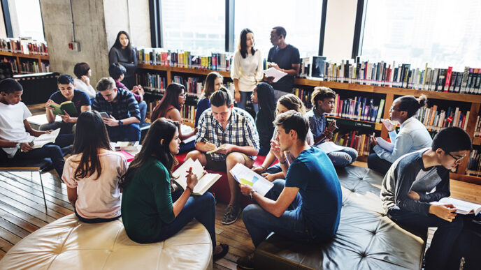 Young adults read and talk in small groups seated in a college library